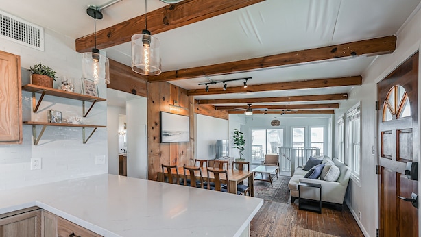A spacious kitchen with wooden beams, a large island, and a dining area with a sofa and chairs. - The Surfsonian - 2nd Row Beach House - Dog Friendly - Ocean View (Freeport)