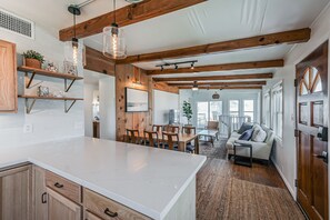 A spacious kitchen with wooden beams, a large island, and a dining area with a sofa and chairs.