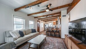 A spacious living room with a sofa, coffee table, and TV. - The Surfsonian - 2nd Row Beach House - Dog Friendly - Ocean View (Freeport)