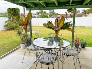 Relax in style with a round table and comfortable seating under a lush green roof.