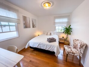 Relax in this serene bedroom with a large bed, bedside table, and comfortable chair.