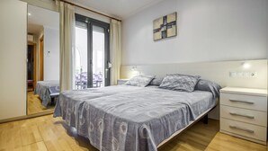 Een slaapkamer met een bed, nachtkastjes, een spiegel en uitzicht door een glazen deur.