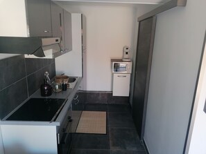 A compact kitchen with a black stove, a microwave, and a small sink.