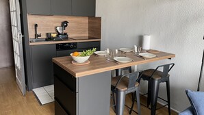 A modern kitchen with a wooden countertop, a built-in oven, and a sink. There is a dining area with a table set for two, including plates, glasses, and cutlery. - Apartment with direct view of the Bay of the Somme (Le Crotoy)