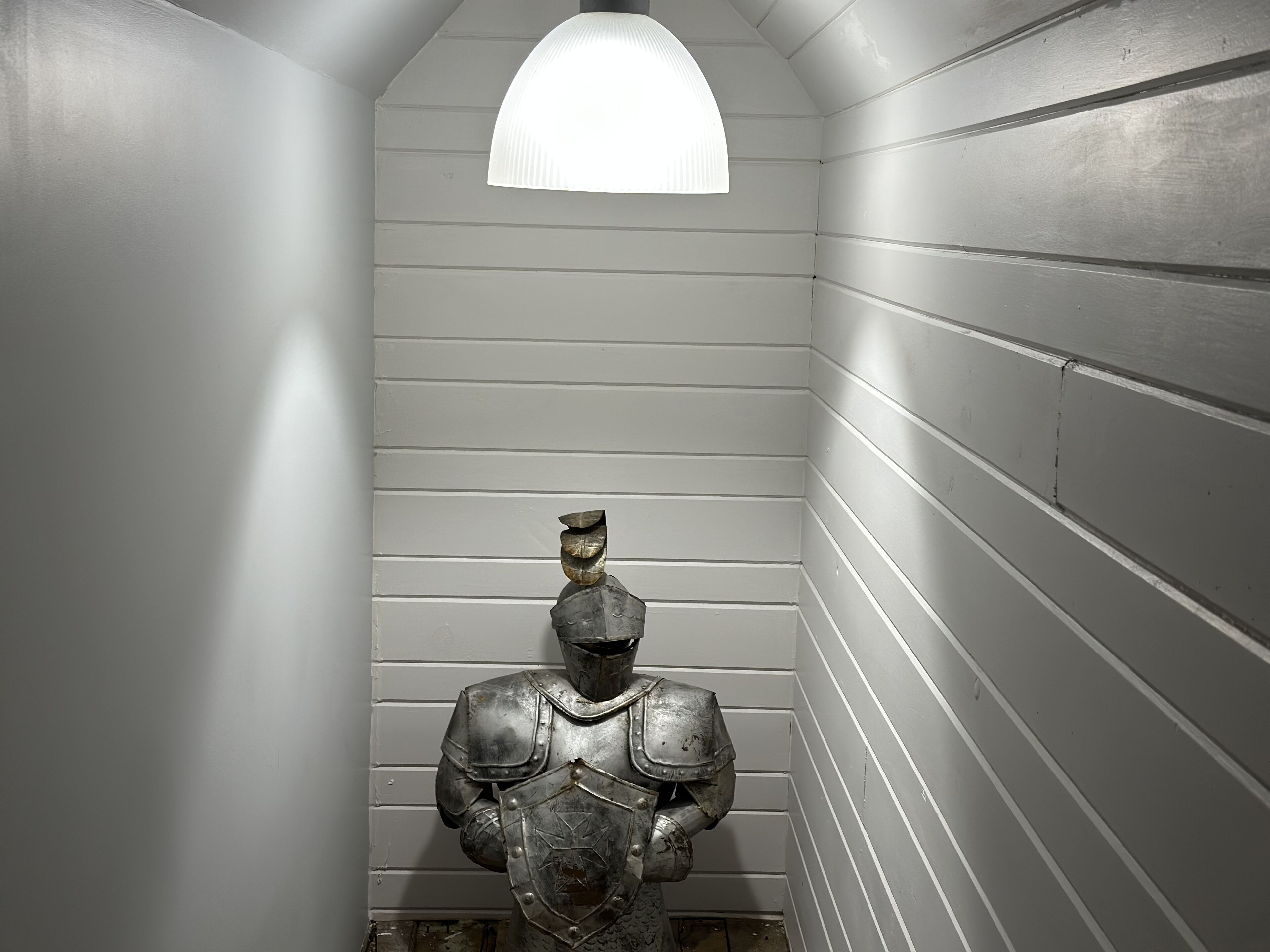 A narrow hallway with white walls and a single light fixture.