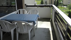 A balcony with a table and chairs, overlooking a residential area with houses and greenery.