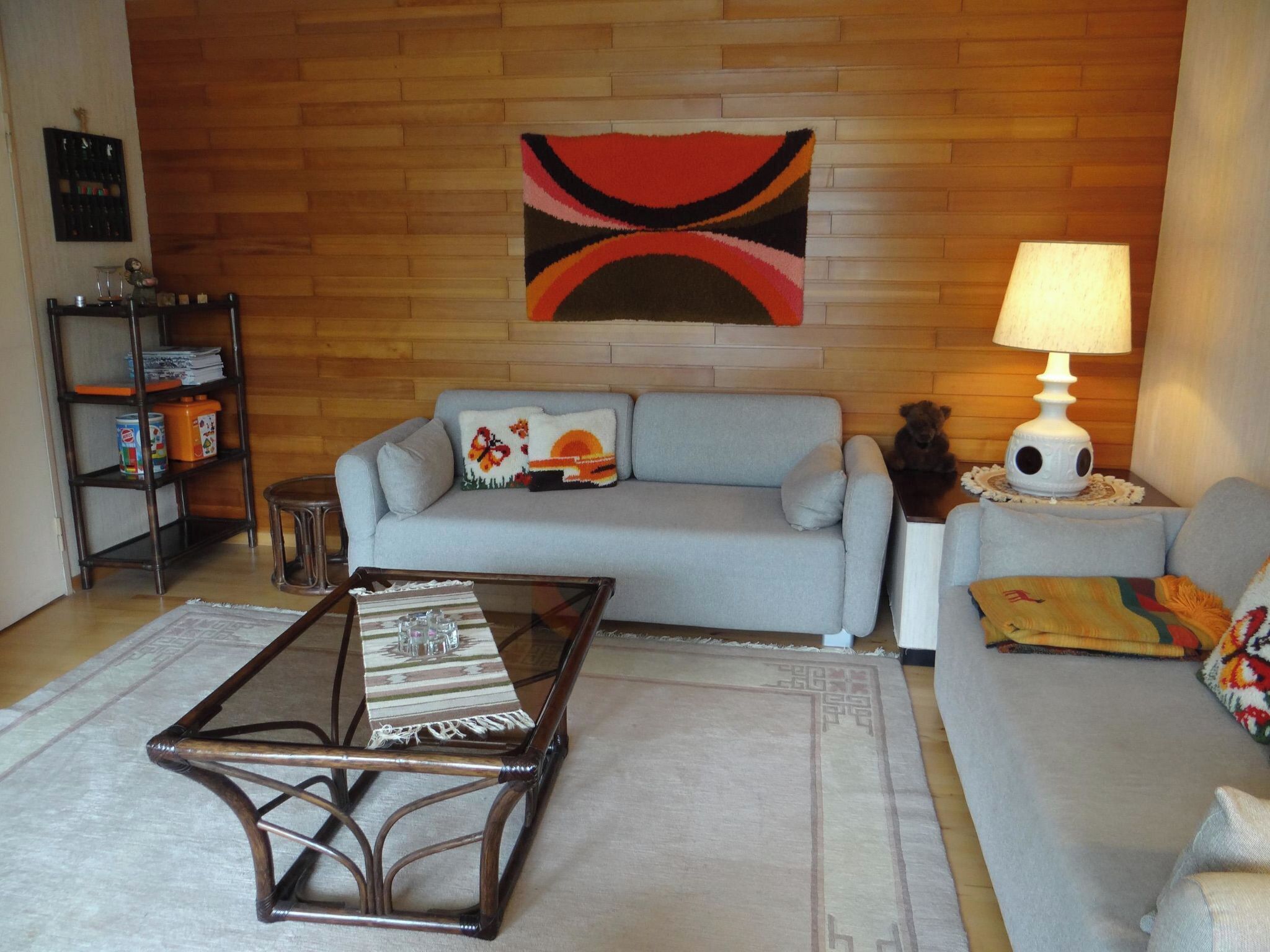 Una sala de estar con un sofá, una mesa de centro, una lámpara y una estantería con objetos.