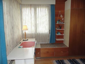 A room with a desk, a lamp, a shelf with various items, a window with curtains, and a wardrobe. - Sunnmatt Süd Wohnung 246 Appartement/Fewo 4-Bettwohnung by Interhome (Engelberg)