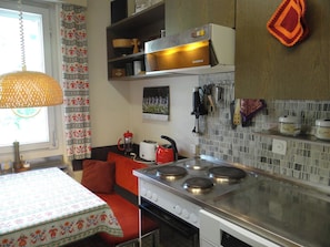 A kitchen with a stove, a sink, and a window with curtains. - Sunnmatt Süd Wohnung 246 Appartement/Fewo 4-Bettwohnung by Interhome (Engelberg)