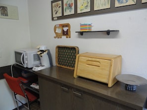 Eine Küchenzeile mit Mikrowelle, Toaster und Holzkasten.