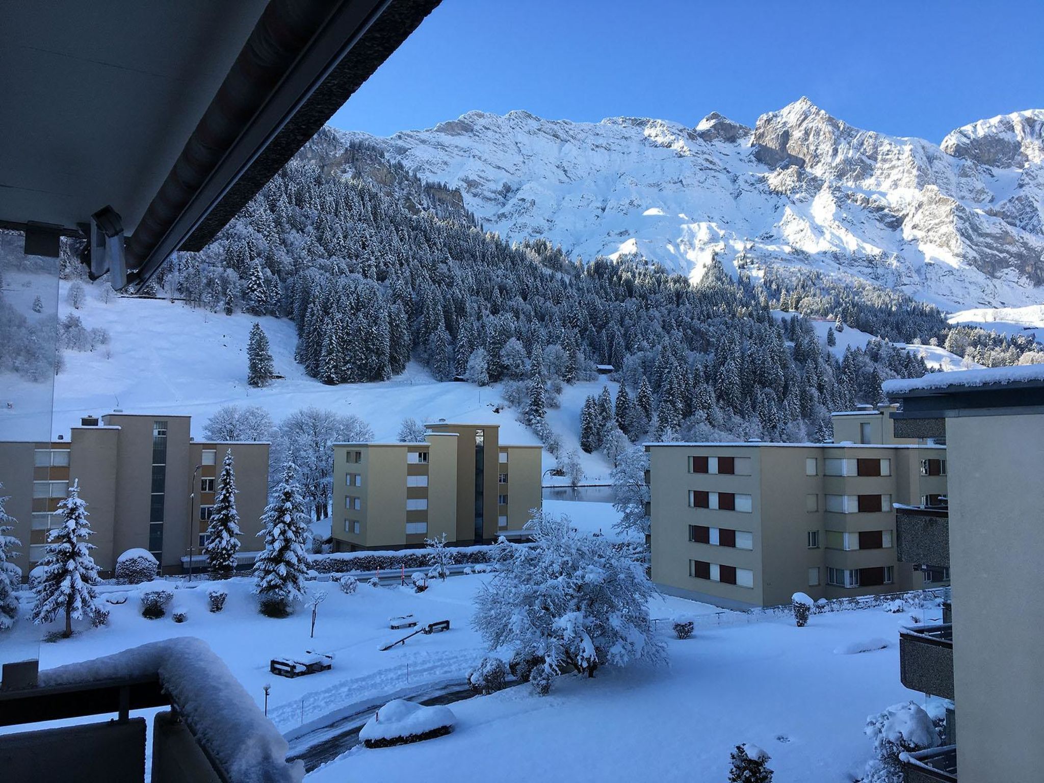 A residential area with snow-covered buildings and a mountainous backdrop.