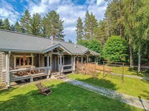 Eine Blockhütte mit Veranda, überdachter Sitzgelegenheit im Freien und einem umzäunten Garten.