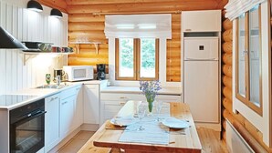 Une cuisine compacte aux murs en bois, une table à manger pour deux personnes et un réfrigérateur.
