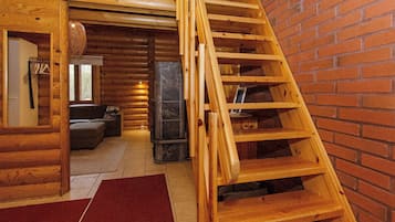 Ein Blockhaus-Interieur mit einer Holztreppe, die zu einem Schlafbereich im oberen Geschoss führt.