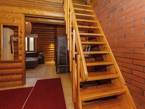 Interior de una cabaña de madera con una escalera de madera que lleva a una zona superior.
