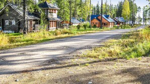 A rural road lined with wooden cabins, some with attached porches and others with separate structures. - Purnutar b by Interhome (Lieksa)
