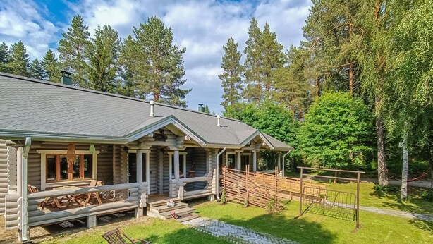 A log cabin with a porch, outdoor seating, and a paved driveway. - Purnutar b by Interhome (Lieksa)