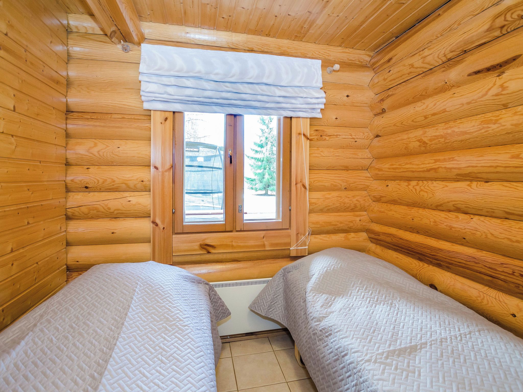 Ein Cabin-Zimmer mit zwei Betten, einem Fenster mit Vorhang und Blick ins Freie.