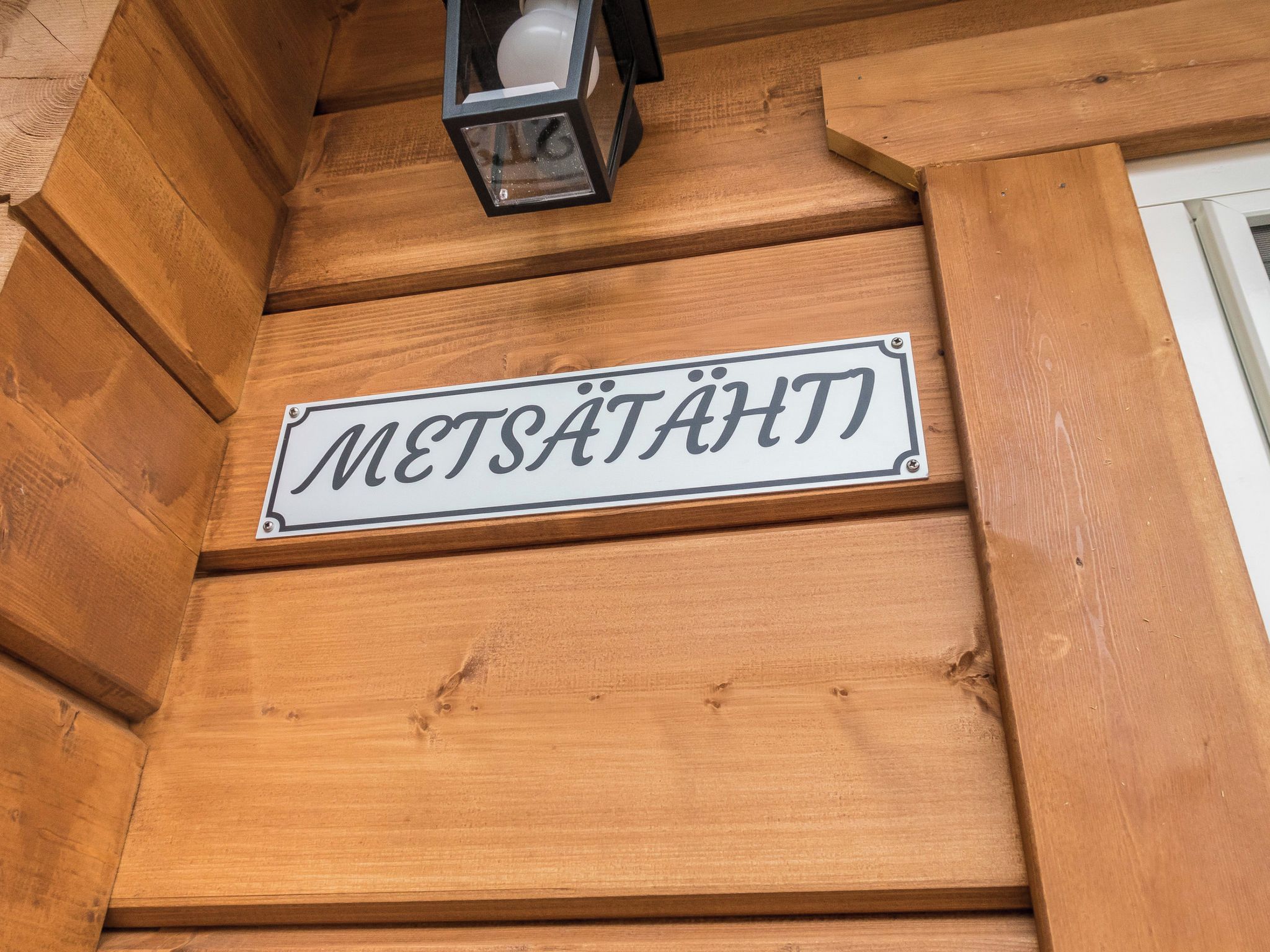 Eine Holzfassade mit einem Schild, auf dem 'METSÄTÄHTT' steht.