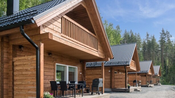 Une cabane en bois dotée d’un porche couvert, de meubles d’extérieur et d’une allée gravillonnée.