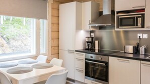 Une cuisine moderne avec des meubles blancs, un four à micro-ondes encastré, une machine à café et un grille-pain.