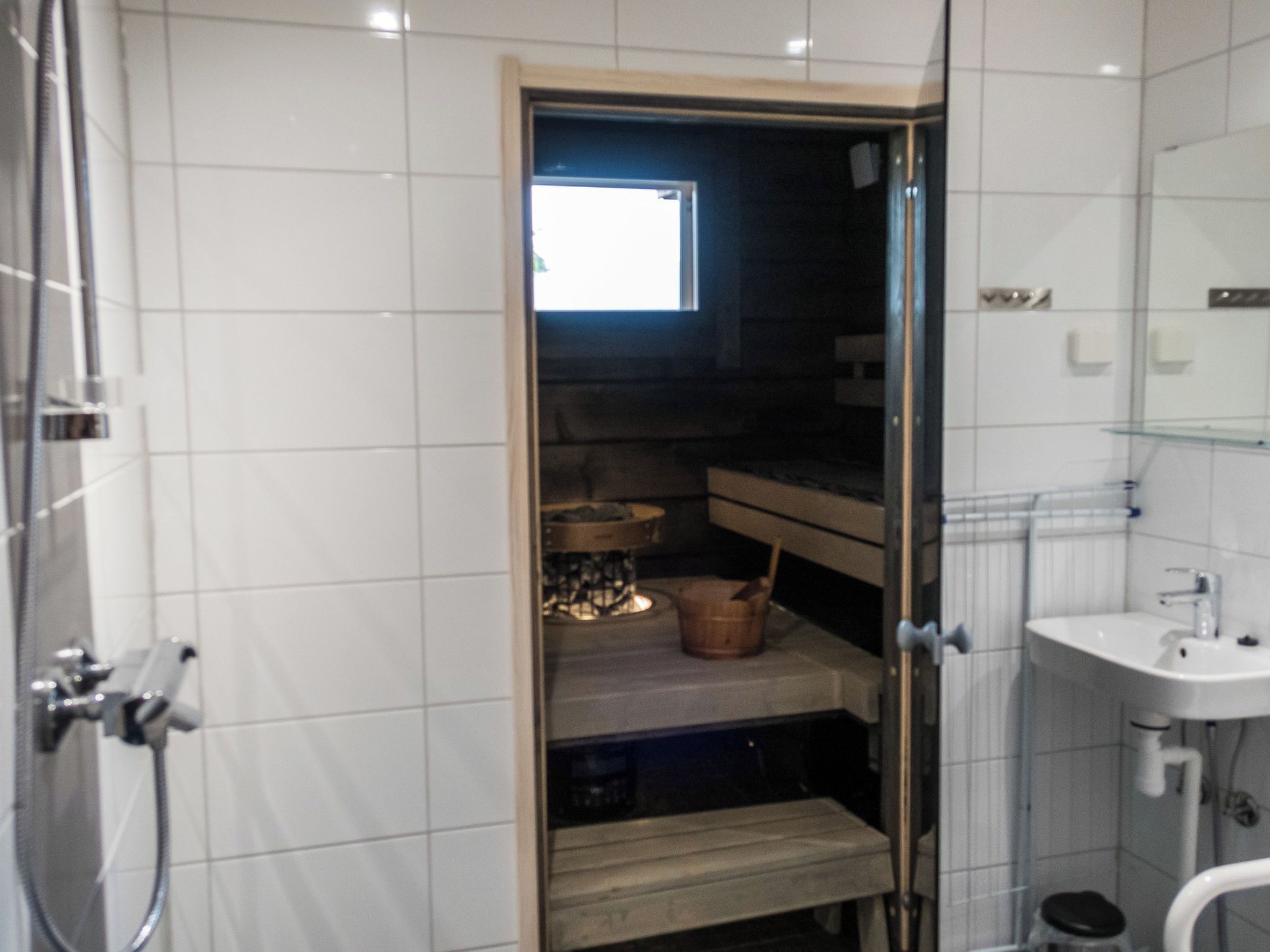 Ein Badezimmer mit Dusche, Waschbecken und Fenster.