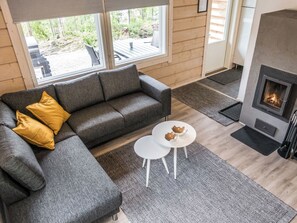 Un salon moderne avec un canapé gris, une petite table blanche et une cheminée.