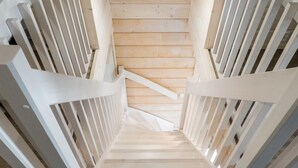 Eine Holztreppe mit weißen Geländern, die zu einer höheren Etage führt.