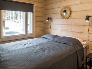 Une chambre à coucher avec un lit, une fenêtre avec des stores, un miroir fixé au mur et deux lampes de chevet.