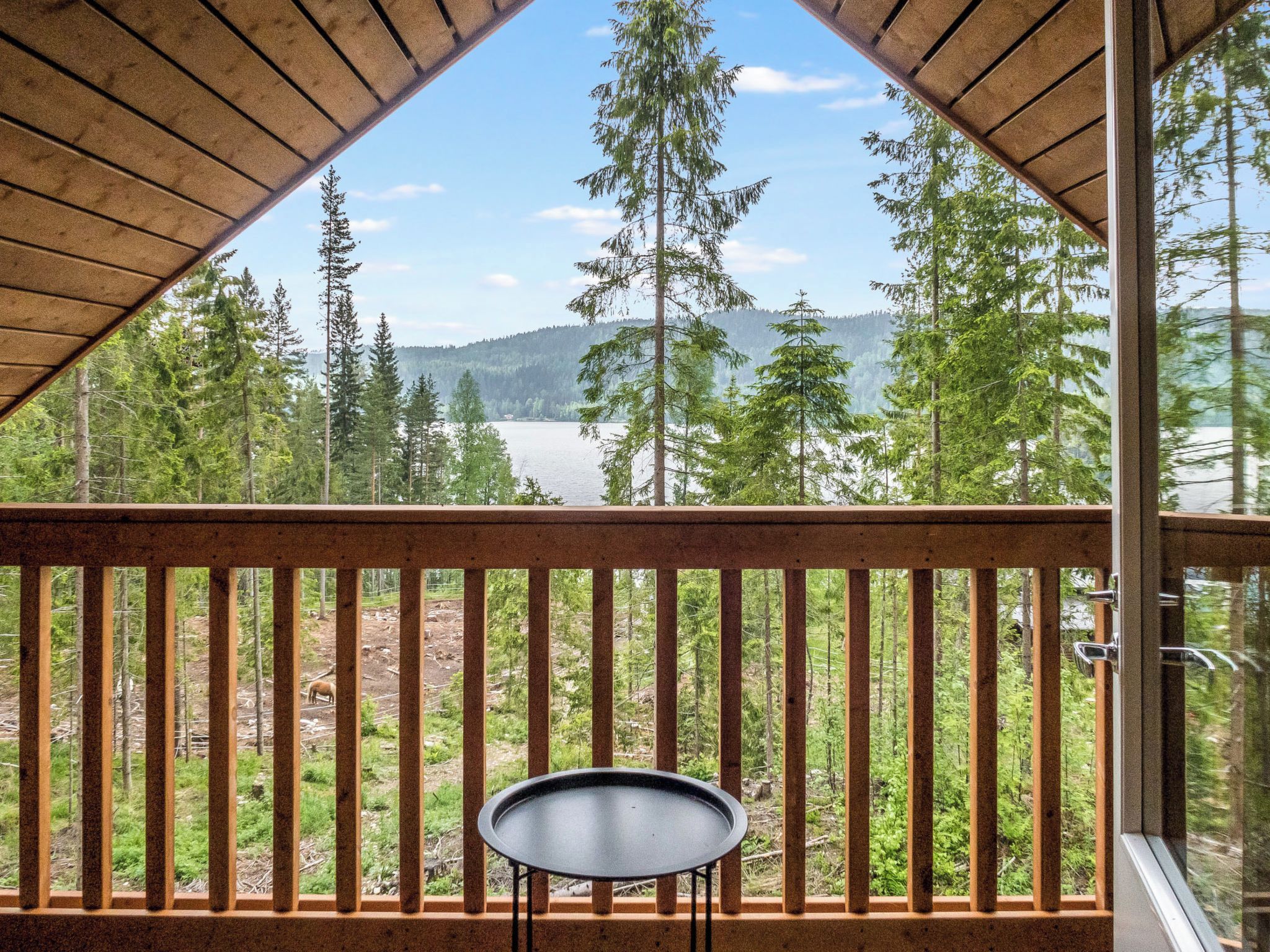 En balkong med utsikt över en skog och en sjö.