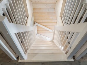 Eine Holztreppe mit weißen Geländern, die zu einer Empore führt.