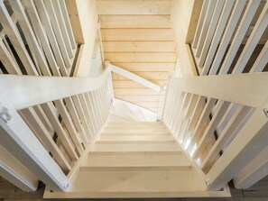 Un escalier en bois avec des rampes blanches menant à un palier.
