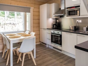 Une cuisine moderne avec des meubles blancs, un four encastré, un four à micro-ondes et une machine à café.