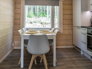 A compact kitchen with a dining table and chairs, a window with a view of trees, and a built-in oven.