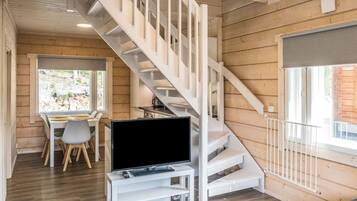 Un interno moderno con una scala in legno, una zona pranzo e un televisore su un mobile bianco.