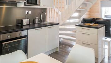 A modern kitchen with stainless steel appliances, a built-in microwave, and a white countertop.