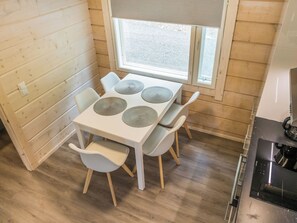 Une cuisine de taille réduite avec une table et des chaises blanches, une fenêtre et une cuisinière.