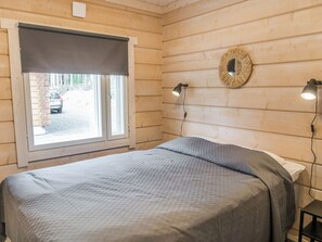 Ein Zimmer mit einem Bett, einem Fenster mit Blick nach draußen und zwei Wandleuchten.
