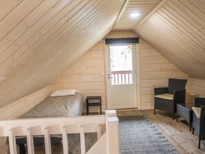 Een knus zolderkamertje met een bed, een stoel en een kleine tafel.