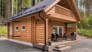 A wooden cabin with a covered porch, a chimney, and a small outdoor seating area.