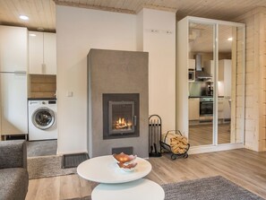 Ein modernes Wohnzimmer mit Kamin, einem Esstisch und einer Küche im Hintergrund.