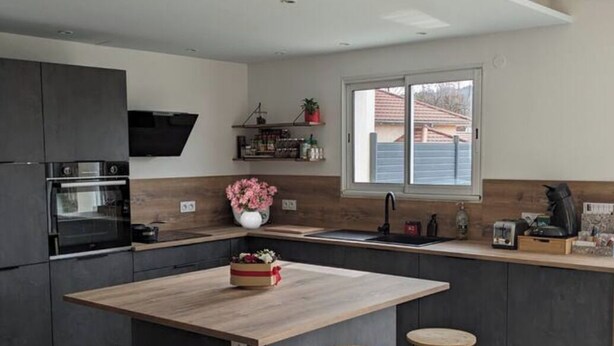 A modern kitchen with a central island, bar stools, and a window providing natural light. - Comfortable family home in the mountains, near lake and resorts (La Rochette)