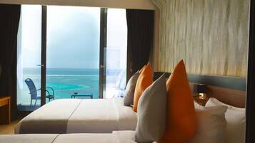 A hotel room with two beds, a view of the ocean, and a large window.