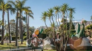 Un parque con palmeras y una gran escultura.