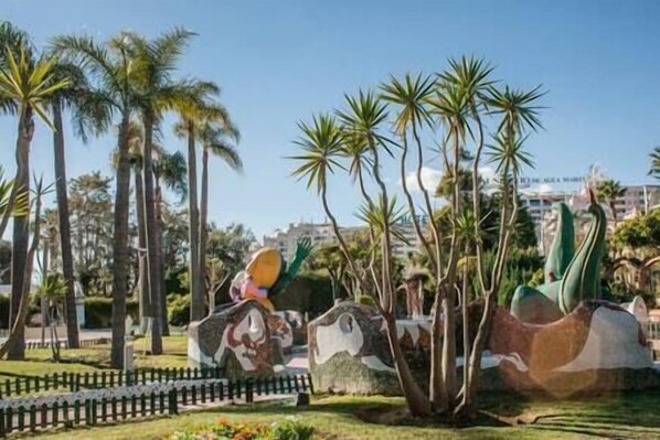 A park with palm trees and a large sculpture.