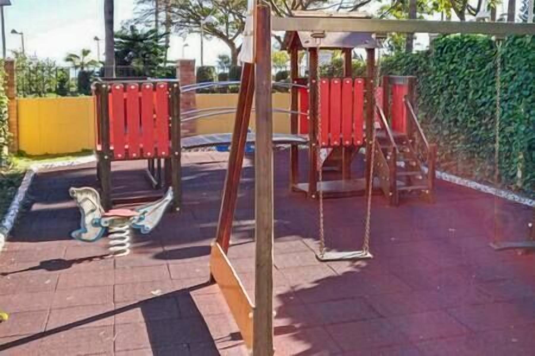 Un parque infantil con columpios y un tobogán.
