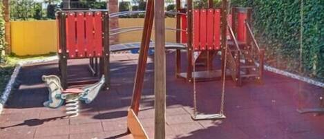 Un parque infantil con columpios y un tobogán.