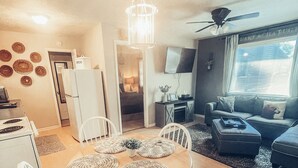 Un salon moderne comprenant un coin repas, une cuisine et une grande fenêtre offrant une vue dégagée.