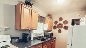 Une cuisine avec des meubles de rangement en bois, un réfrigérateur blanc, une cuisinière et un four à micro-ondes.
