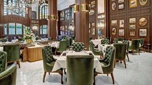 Een luxueus eetgedeelte met groen bekleden stoelen, witte tafelkleden en een kroonluchter.